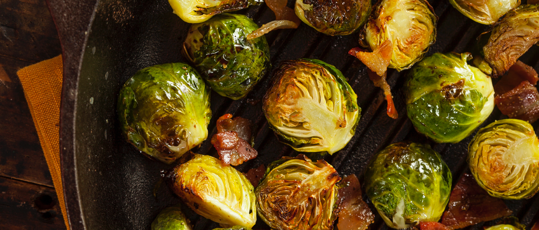Grilled Brussel sprouts with bacon cooking in a pan