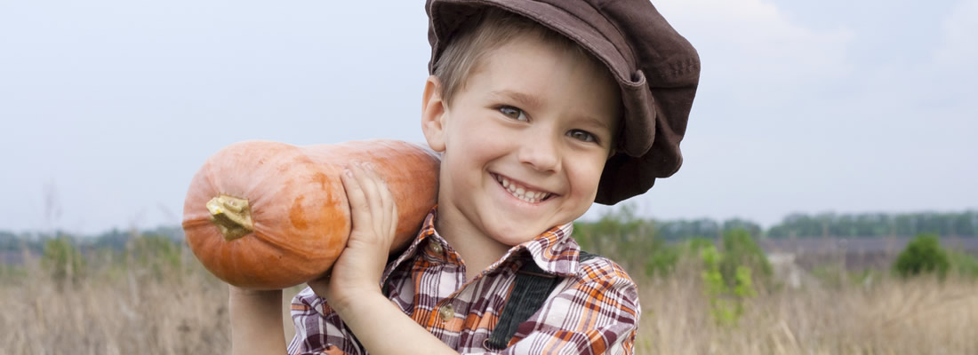 A young boy holding a squash on his shoulder